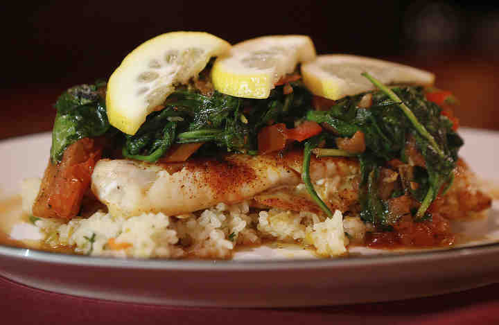 Scrod plaki with sautéed onion, roasted roma tomato and spinach on a bed of rice at Wise Guys in Akron's North Hill neighborhood.     (Leah Klafczynski / Akron Beacon Journal)